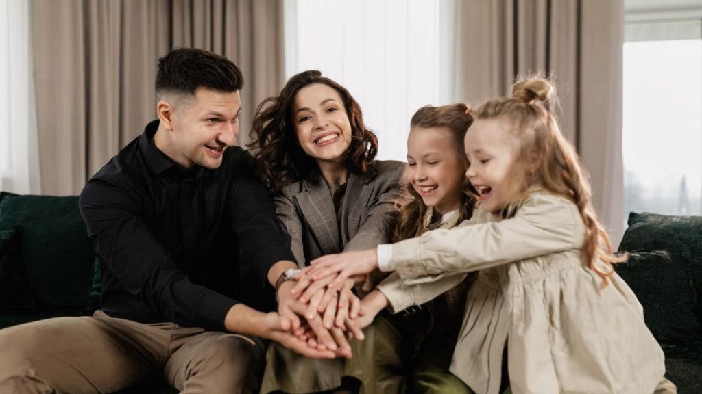 A cheerful family of four bonding together indoors with smiles and joy.